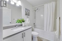 Full bathroom with tile patterned flooring, vanity, toilet, and shower / bath combo with shower curtain - 