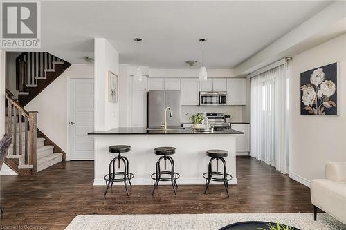 Kitchen featuring white cabinets, pendant lighting, stainless steel appliances, and a breakfast bar area - 577 Goldenrod Lane, Kitchener, ON - Indoor Photo Showing Other Room