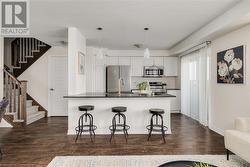 Kitchen featuring white cabinets, pendant lighting, stainless steel appliances, and a breakfast bar area - 