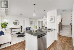 Kitchen featuring hanging light fixtures, dark hardwood / wood-style flooring, sink, and stainless steel dishwasher - 