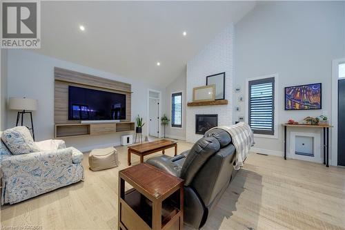 Living room featuring a brick fireplace, light wood-type flooring, high vaulted ceiling, and a healthy amount of sunlight - 33 Madwayosh Street, Southampton, ON - Indoor Photo Showing Living Room With Fireplace