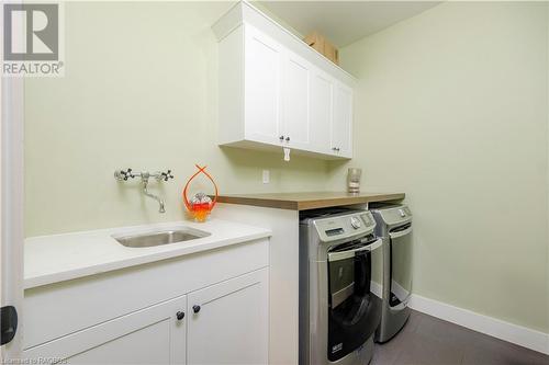 Laundry area featuring cabinets, dark tile patterned floors, sink, and washing machine and dryer - 33 Madwayosh Street, Southampton, ON - Indoor Photo Showing Laundry Room