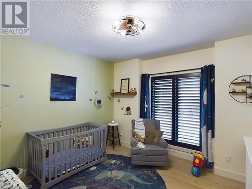 Bedroom featuring a textured ceiling, hardwood / wood-style flooring, and a nursery area - 33 Madwayosh Street, Southampton, ON - Indoor Photo Showing Bedroom