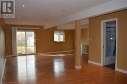 Empty room with beam ceiling, light hardwood / wood-style floors, and a textured ceiling - 