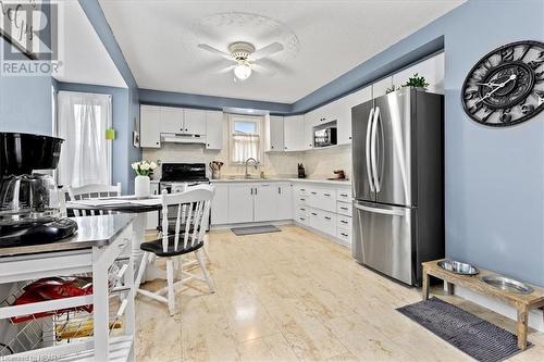 Kitchen with ceiling fan, sink, backsplash, white cabinets, and black appliances - 830 Elma Street W, Listowel, ON - Indoor