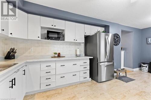 Kitchen with white cabinets, sink, backsplash, and stainless steel refrigerator - 830 Elma Street W, Listowel, ON - Indoor Photo Showing Kitchen