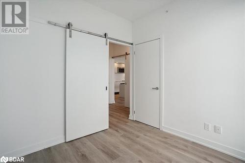 Unfurnished bedroom with a barn door and light wood-type flooring - 370 Martha Street Unit# 2104, Burlington, ON - Indoor Photo Showing Other Room