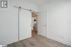 Unfurnished bedroom with a barn door and light wood-type flooring - 