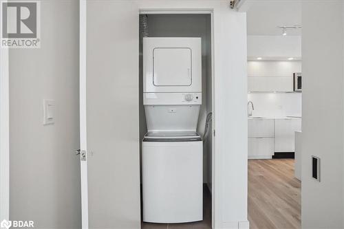 Laundry area with sink, stacked washer and clothes dryer, and light wood-type flooring - 370 Martha Street Unit# 2104, Burlington, ON - Indoor Photo Showing Laundry Room