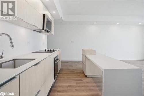 Kitchen featuring stainless steel oven, sink, black electric cooktop, a kitchen island, and light wood-type flooring - 370 Martha Street Unit# 2104, Burlington, ON - Indoor Photo Showing Kitchen