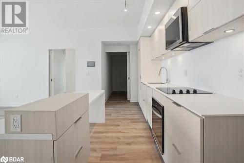 Kitchen with sink, range hood, light hardwood / wood-style floors, black electric cooktop, and light brown cabinetry - 370 Martha Street Unit# 2104, Burlington, ON - Indoor Photo Showing Kitchen With Upgraded Kitchen