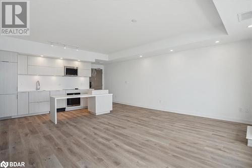 Kitchen featuring a raised ceiling, light hardwood / wood-style floors, a kitchen island, and stainless steel appliances - 370 Martha Street Unit# 2104, Burlington, ON - Indoor Photo Showing Kitchen