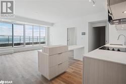 Kitchen with a center island, a water view, sink, light brown cabinetry, and light hardwood / wood-style floors - 