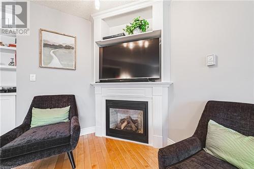 Living area featuring light wood-type flooring and a textured ceiling - 145 Dragoon Drive, Hamilton, ON - Indoor Photo Showing Living Room With Fireplace