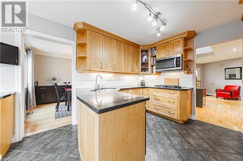 Kitchen with a skylight, sink, stainless steel appliances, dark hardwood / wood-style flooring, and backsplash - 145 Dragoon Drive, Hamilton, ON - Indoor Photo Showing Kitchen