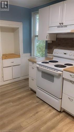 Kitchen featuring tasteful backsplash, white range with electric cooktop, light hardwood / wood-style flooring, and white cabinets - 49 Robins Avenue Unit# 3, Hamilton, ON 