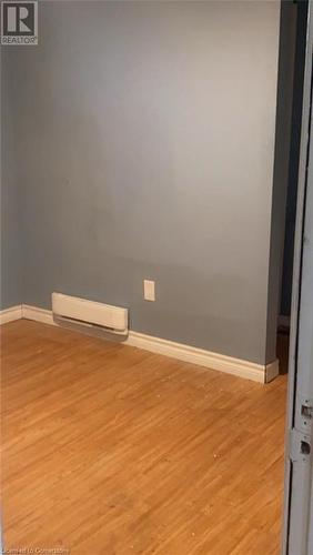 Unfurnished room featuring light wood-type flooring and a baseboard radiator - 49 Robins Avenue Unit# 3, Hamilton, ON 