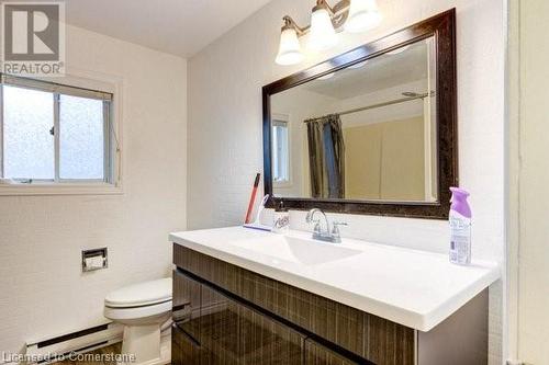 Bathroom featuring hardwood / wood-style floors, vanity, a baseboard heating unit, toilet, and curtained shower - 539 Briarwood Avenue, Listowel, ON - Indoor Photo Showing Bathroom