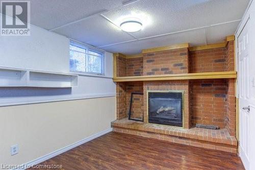 Unfurnished living room featuring hardwood / wood-style floors, a textured ceiling, and a brick fireplace - 539 Briarwood Avenue, Listowel, ON - Indoor With Fireplace