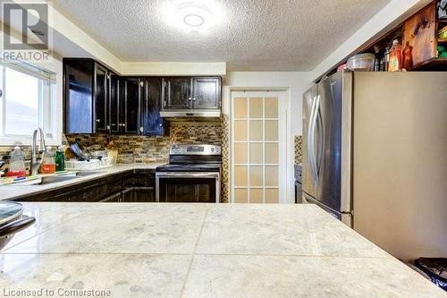 Kitchen featuring a textured ceiling, decorative backsplash, sink, and stainless steel appliances - 539 Briarwood Avenue, Listowel, ON - Indoor Photo Showing Kitchen