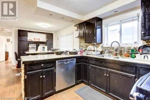 Kitchen with tasteful backsplash, dark brown cabinetry, sink, light hardwood / wood-style flooring, and dishwasher - 539 Briarwood Avenue, Listowel, ON - Indoor Photo Showing Kitchen With Double Sink