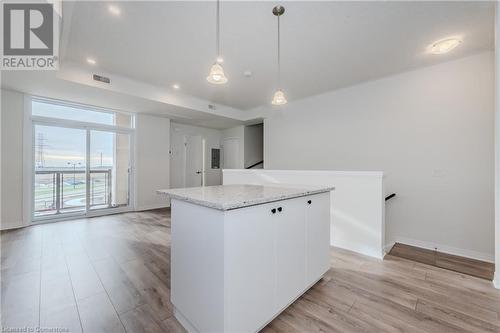 Kitchen with white cabinets, pendant lighting, light hardwood / wood-style flooring, and a kitchen island - 142 Foamflower Place Unit# D059, Waterloo, ON - Indoor Photo Showing Kitchen