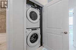 Laundry area featuring light tile patterned floors and stacked washer / dryer - 