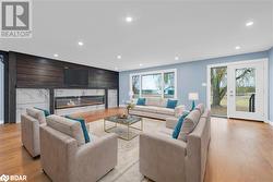 Living room featuring a high end fireplace, light hardwood / wood-style flooring, and a healthy amount of sunlight - 