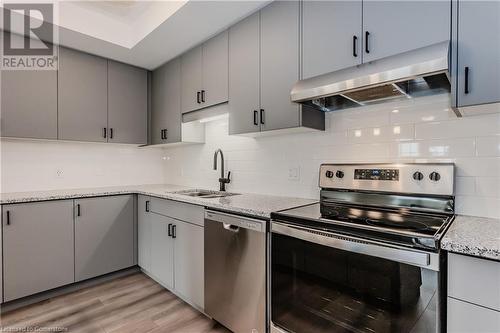 Kitchen with sink, decorative backsplash, appliances with stainless steel finishes, light hardwood / wood-style floors, and light stone counters - 142 Foamflower Place Unit# D053, Waterloo, ON - Indoor Photo Showing Kitchen With Double Sink With Upgraded Kitchen