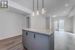 Kitchen featuring gray cabinetry, decorative light fixtures, french doors, and light hardwood / wood-style flooring - 