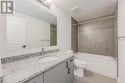 Full bathroom with tiled shower / bath combo, tile patterned flooring, a textured ceiling, toilet, and vanity - 