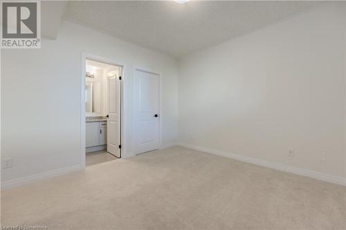 Unfurnished bedroom with light colored carpet, a textured ceiling, and ensuite bath - 142 Foamflower Place Unit# D053, Waterloo, ON - Indoor Photo Showing Other Room