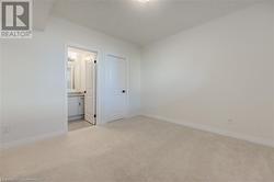 Unfurnished bedroom with light colored carpet, a textured ceiling, and ensuite bath - 