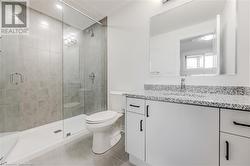 Bathroom featuring tile patterned floors, vanity, toilet, and walk in shower - 