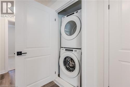 Laundry room featuring a textured ceiling, wood-type flooring, and stacked washer / drying machine - 142 Foamflower Place Unit# D053, Waterloo, ON - Indoor Photo Showing Laundry Room