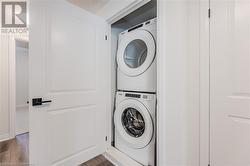 Laundry room featuring a textured ceiling, wood-type flooring, and stacked washer / drying machine - 