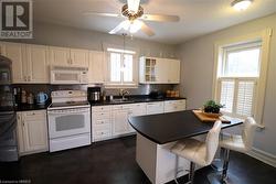 Kitchen featuring tasteful backsplash, white appliances, ceiling fan, sink, and white cabinetry - 