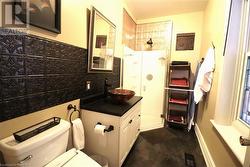 Bathroom featuring vanity, toilet, walk in shower, and tasteful backsplash - 