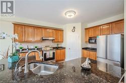 Kitchen featuring dark stone countertops, sink, appliances with stainless steel finishes, and tasteful backsplash - 