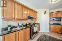 Kitchen with tasteful backsplash, extractor fan, stainless steel range with electric stovetop, and black microwave - 