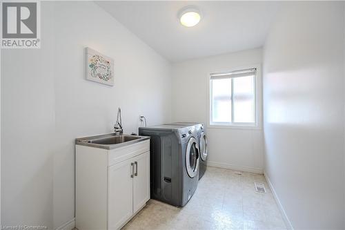 Clothes washing area with cabinets, washing machine and dryer, and sink - 584 Winterburg Walk, Waterloo, ON - Indoor Photo Showing Laundry Room