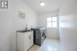 Clothes washing area with cabinets, washing machine and dryer, and sink - 