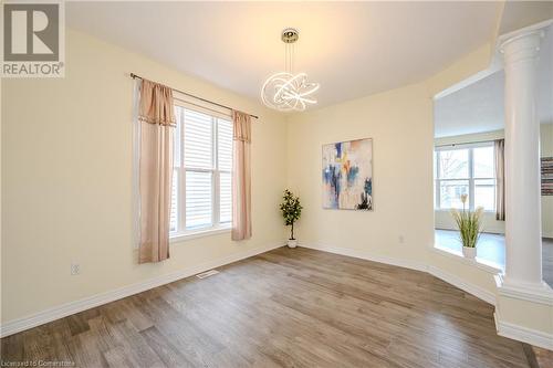 Empty room featuring decorative columns, wood-type flooring, a wealth of natural light, and a chandelier - 584 Winterburg Walk, Waterloo, ON - Indoor Photo Showing Other Room