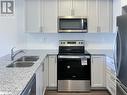 Kitchen featuring light stone countertops, sink, white cabinets, and appliances with stainless steel finishes - 1581 Rose Way Unit# 513, Milton, ON  - Indoor Photo Showing Kitchen With Stainless Steel Kitchen With Double Sink With Upgraded Kitchen 