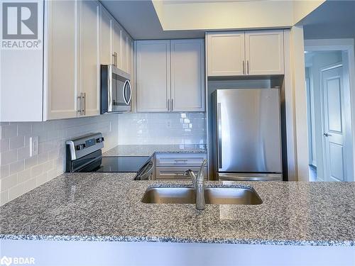 Kitchen with decorative backsplash, stainless steel appliances, light stone countertops, and sink - 1581 Rose Way Unit# 513, Milton, ON - Indoor Photo Showing Kitchen With Stainless Steel Kitchen With Double Sink With Upgraded Kitchen