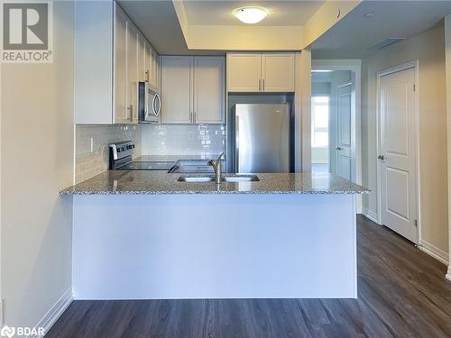 Kitchen with light stone countertops, sink, kitchen peninsula, and stainless steel appliances - 1581 Rose Way Unit# 513, Milton, ON - Indoor Photo Showing Kitchen With Double Sink