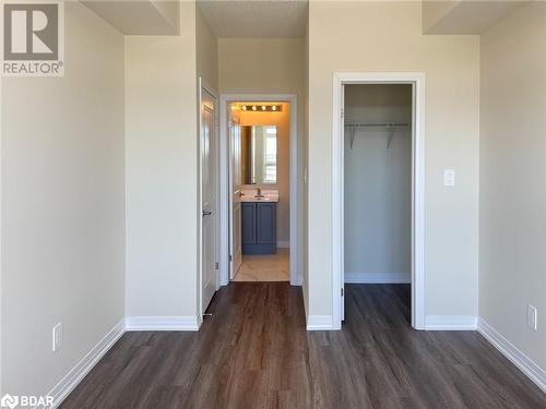 Unfurnished bedroom featuring ensuite bath, a spacious closet, dark wood-type flooring, and a closet - 1581 Rose Way Unit# 513, Milton, ON - Indoor Photo Showing Other Room