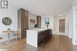 Kitchen featuring a kitchen island with sink, light wood-type flooring, sink, and a breakfast bar - 