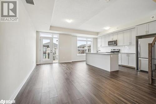 Kitchen with appliances with stainless steel finishes, backsplash, a kitchen island with sink, sink, and dark hardwood / wood-style floors - 1569 Rose Way Unit# 104, Milton, ON - Indoor Photo Showing Kitchen With Stainless Steel Kitchen With Upgraded Kitchen