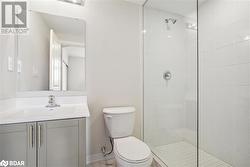 Bathroom with a tile shower, vanity, and toilet - 